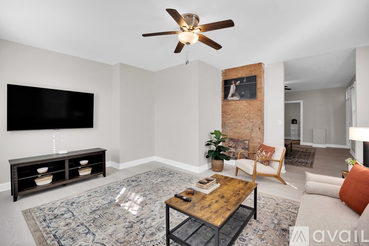A living room with a flat screen TV, a wooden coffee table, and a ceiling fan.