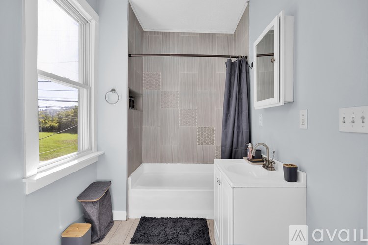 A bathroom with a white tub and grey shower curtain.