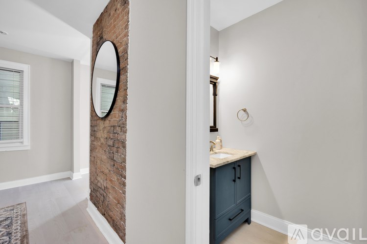 A bathroom with a round mirror and a brick wall.