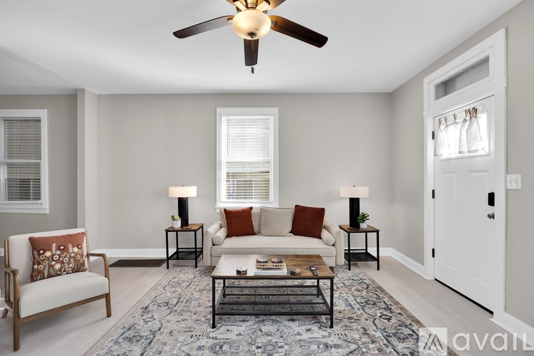 A living room with a sofa, a chair, a coffee table, and a ceiling fan.
