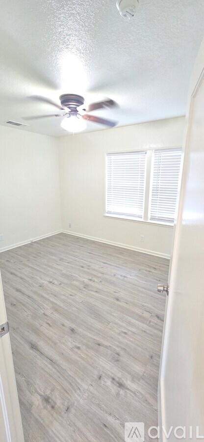 A room with a ceiling fan and wooden flooring.