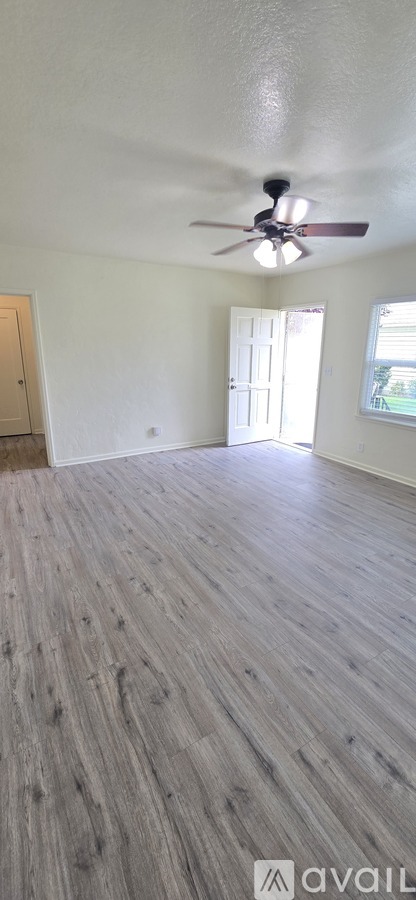 A room with a ceiling fan and wooden flooring.