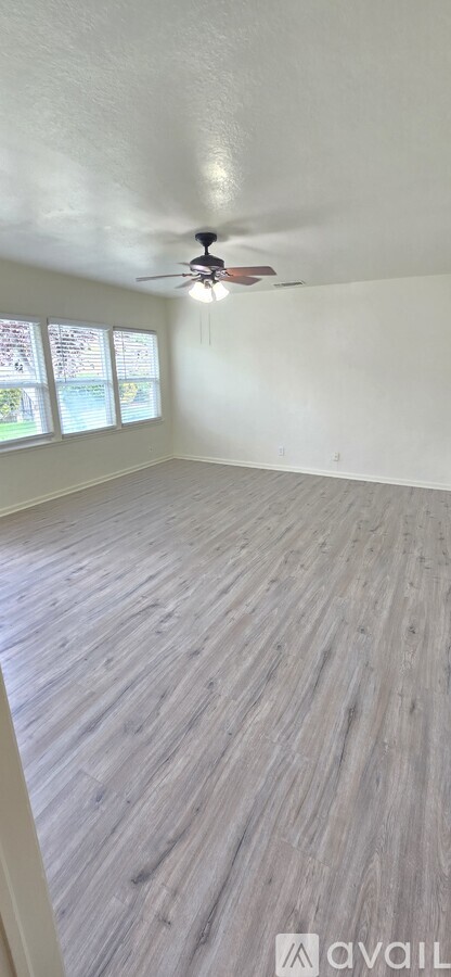 A room with a ceiling fan and wooden flooring.