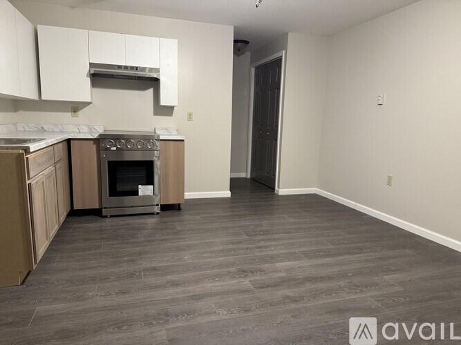 A kitchen with a stove top oven and a wooden floor.