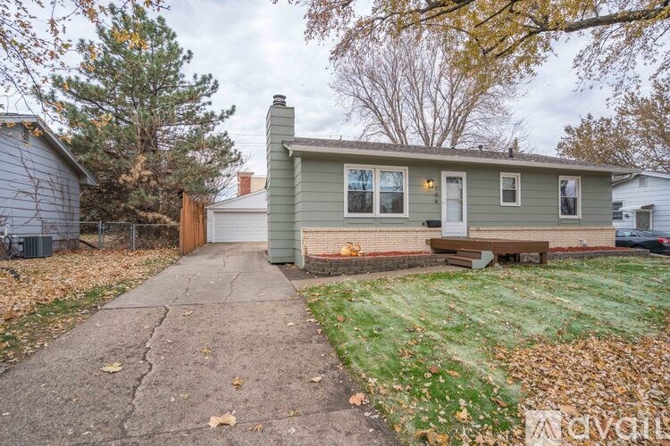 A house with a grey roof and a brown bench in front of it.