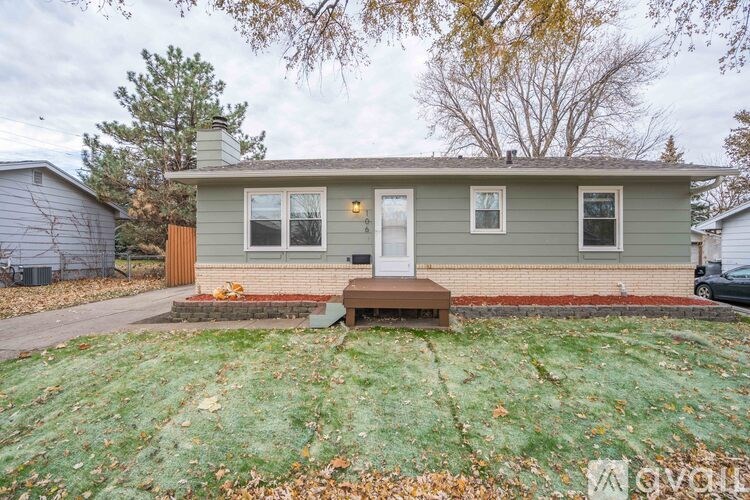 A small house with a brown door and a brown bench in front of it.