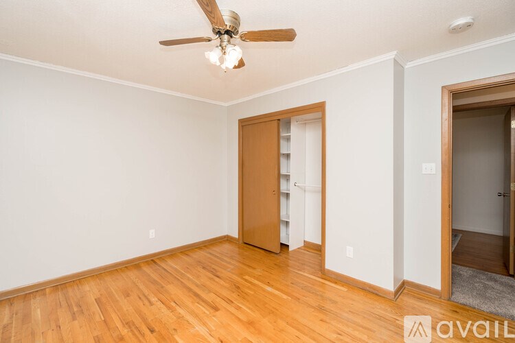 A room with a ceiling fan and wooden floors.