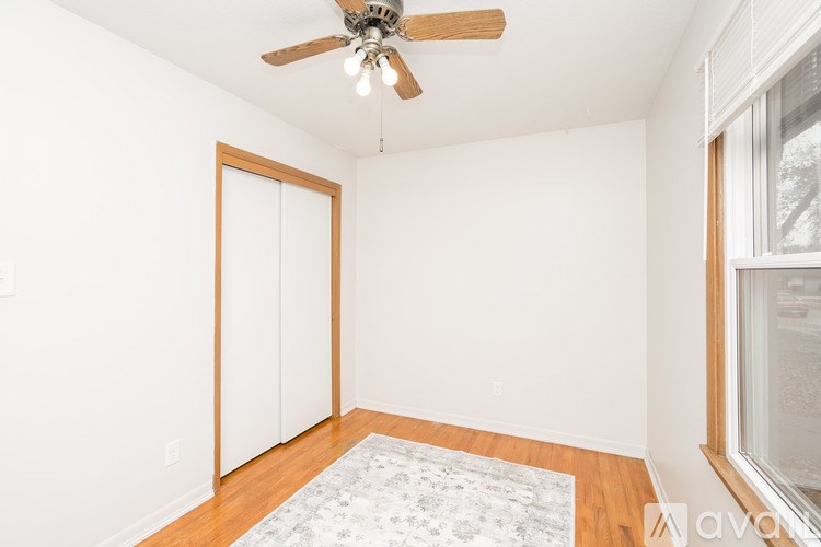 A room with a ceiling fan and a rug on the floor.