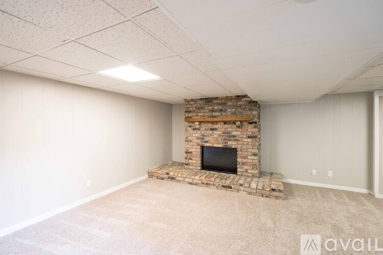 A room with a stone fireplace and carpeted floor.