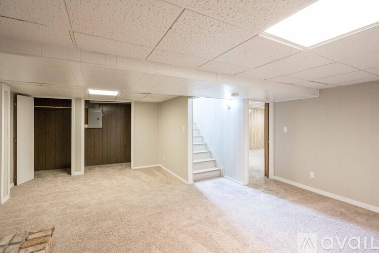 A spacious room with a staircase leading to another room.