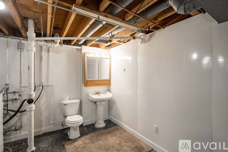 A bathroom with a toilet, sink, and mirror.