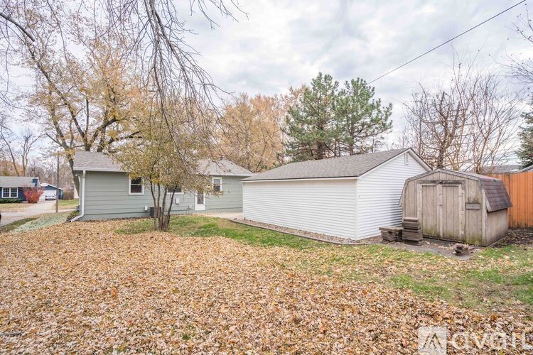 A house with a shed and a tree with no leaves.