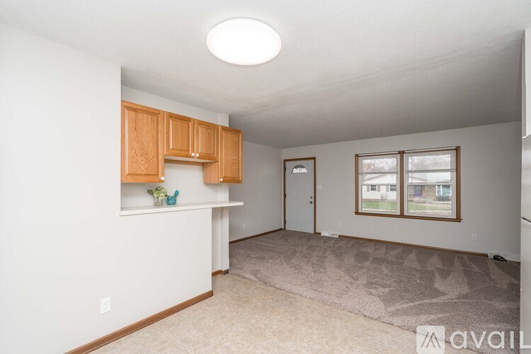 A room with a carpeted floor and a window with a view of a house.