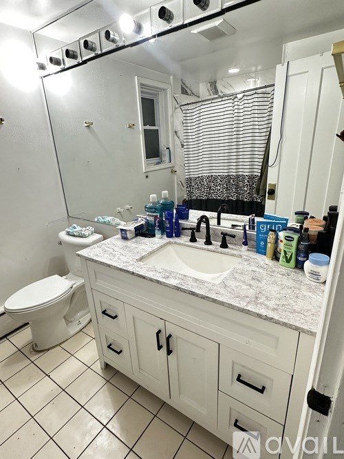 A bathroom with a white toilet, sink, and cabinets.