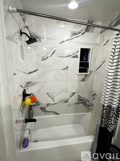 A white bathtub with a shower head and a small screen on the wall.