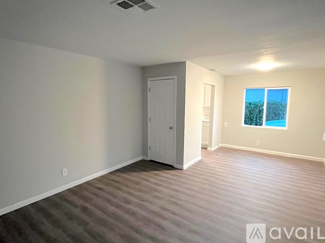A room with a carpeted floor, a door, and a window showing a blue sky.