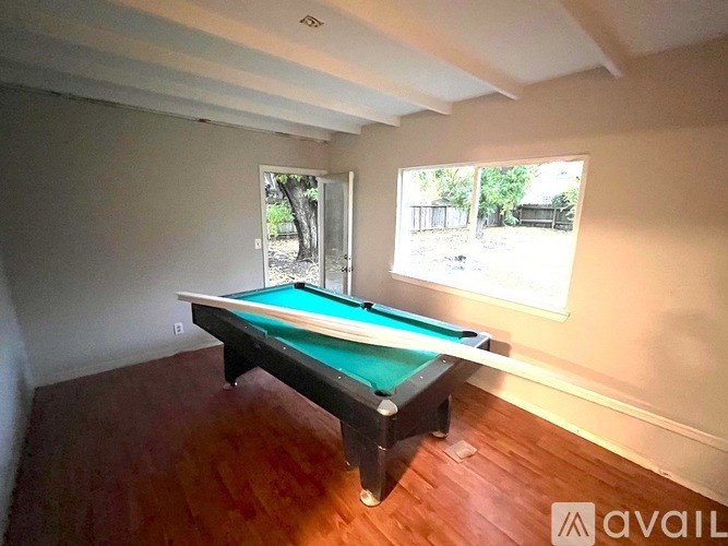 A pool table in a room with a window.
