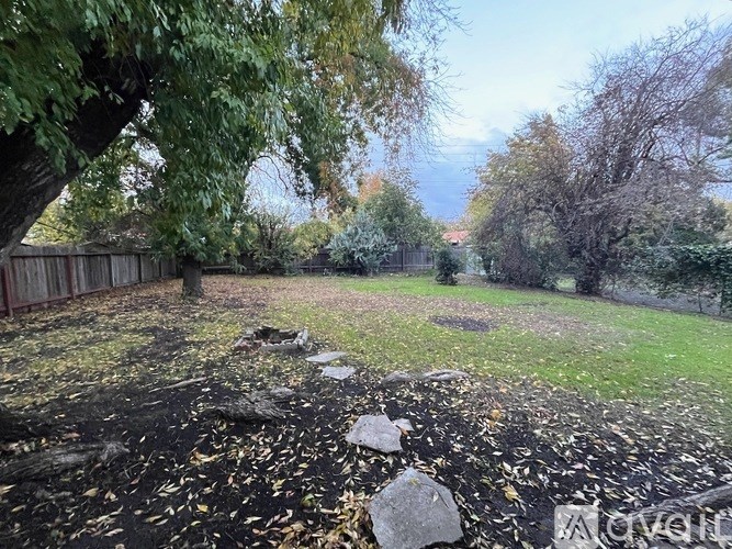 A backyard with a dirt area and a fence.