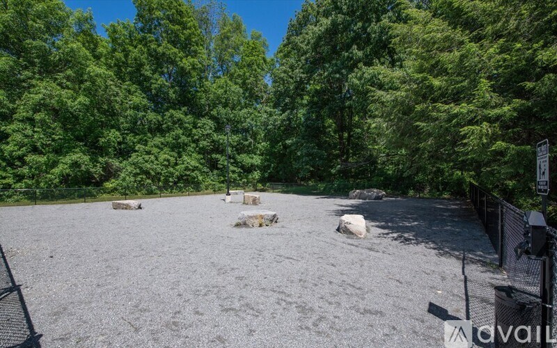 A gravel area surrounded by trees with a sign on the right.