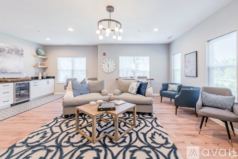 A living room with a patterned rug and a coffee table in the center.