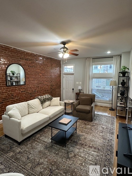 A living room with a white couch, a brown chair, and a rug.