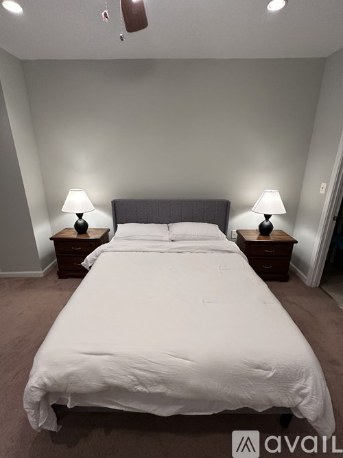A bed with white sheets and two lamps on either side of it.