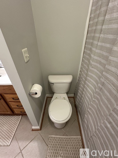 A white toilet in a small bathroom with a grey shower curtain.