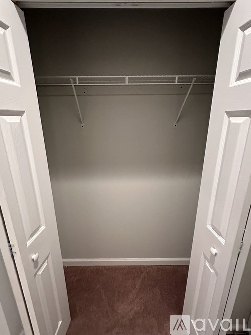 A white closet with a shelf and a door.