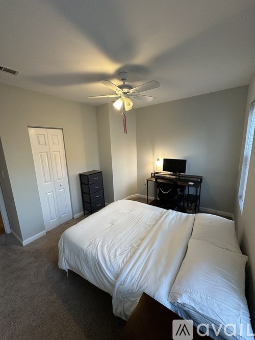 A bedroom with a bed, dresser, and ceiling fan.
