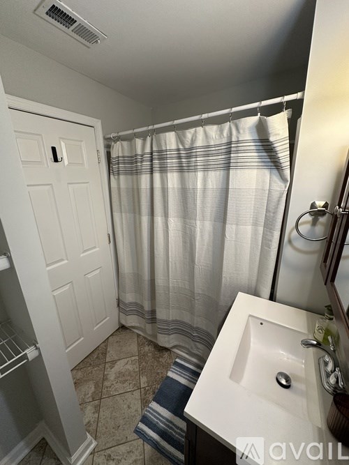 A bathroom with a white sink and a shower curtain.