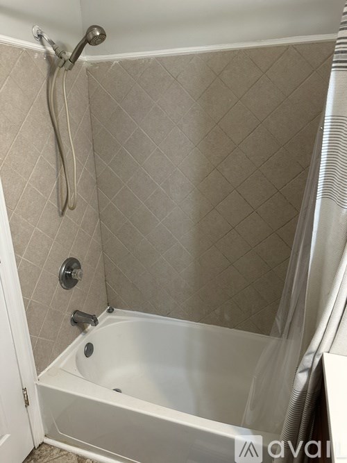 A white bathtub with a shower head and a hose.