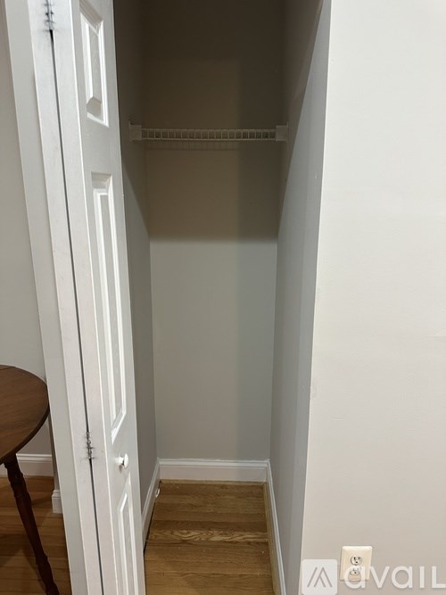 A small white closet with a shelf and a table.