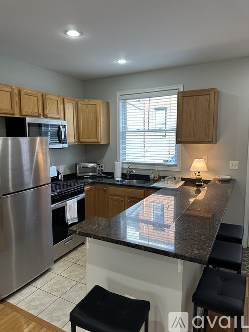 A kitchen with a black counter top and stainless steel appliances.