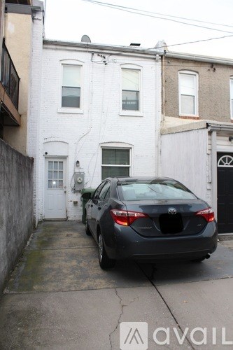 A black car is parked in front of a white building.