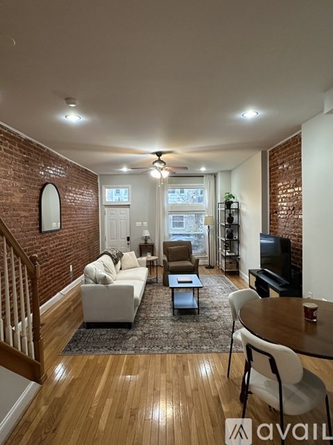 A living room with a white couch and a wooden floor.