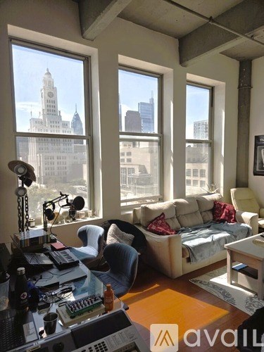 A room with a desk and a couch with a view of a city skyline.