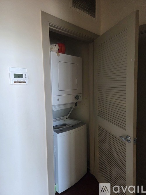 A small white refrigerator is in a narrow hallway.