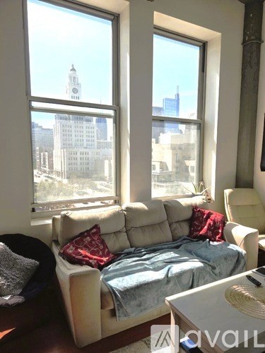 A living room with a couch and a bed in front of a window.