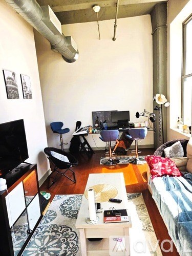 A living room with a television, a couch, a chair, a coffee table, and a rug.
