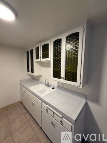 A white sink and cabinets under a window.