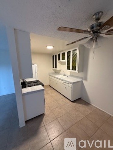 A room with a fan, a stove, and a fridge.