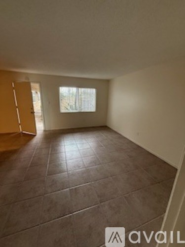 A room with brown tiles on the floor and a window letting in light.