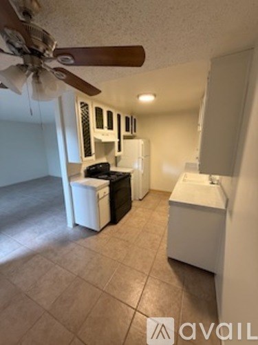 A room with a fan, a sink, and a fridge.