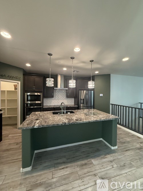 A kitchen with granite countertops and a stainless steel refrigerator.