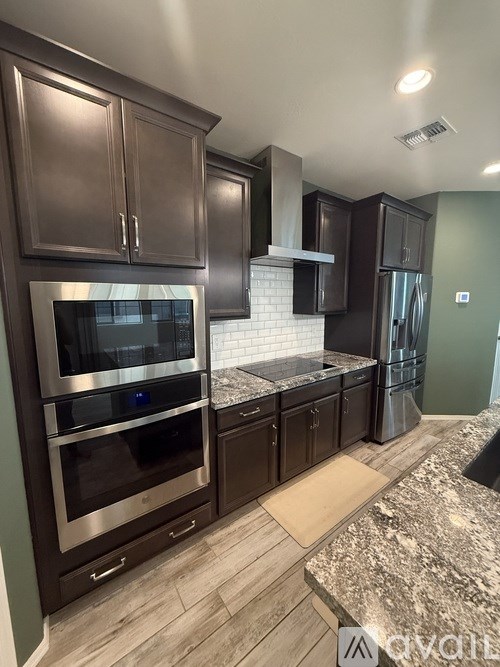 A kitchen with dark wood cabinets and granite countertops.