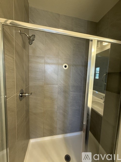 A bathroom with a glass shower door and a white tub.