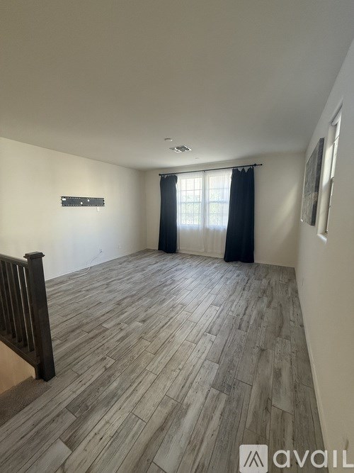 A room with wooden flooring and a window with curtains.