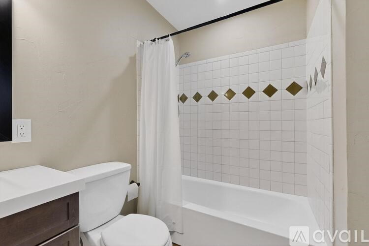 A white toilet sits next to a white bathtub in a bathroom.