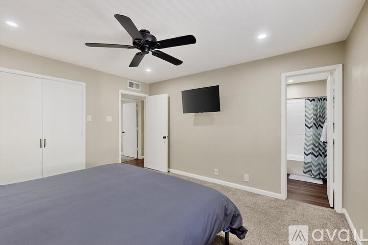 A bedroom with a bed, a ceiling fan, and a television.
