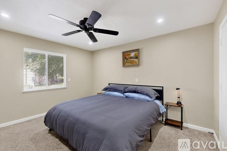 A bedroom with a bed, nightstand, and a ceiling fan.